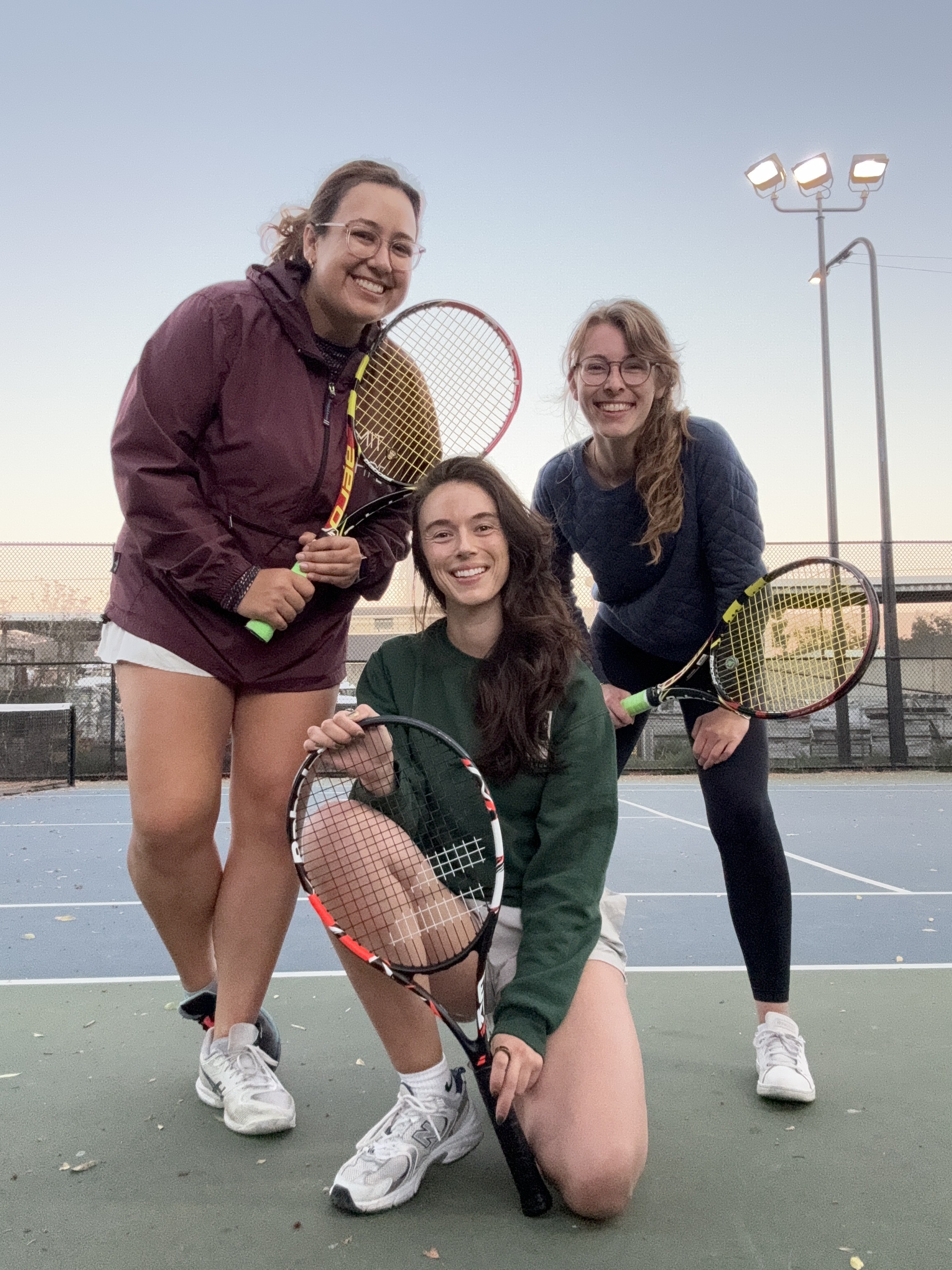 Co-Design Lab members Nicole, Caseysimone, and Gaelle holding tennis rackets on a tennis court